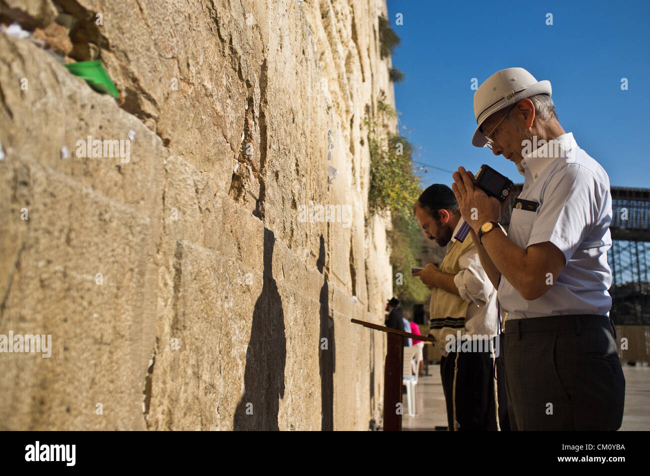 A Hibakusha, a Hiroshima child survivor, prays at the Western Wall besides a religious Jew. Jerusalem, Israel. 10-September-2012.  Hibakusha, survivors of the August 6th, 1945 bombing of Hiroshima, visit Israel to promote nuclear abolition. Calling “No More Hiroshimas, No More Nagasakis!” they place their prayers between the Kotel stones. Stock Photo