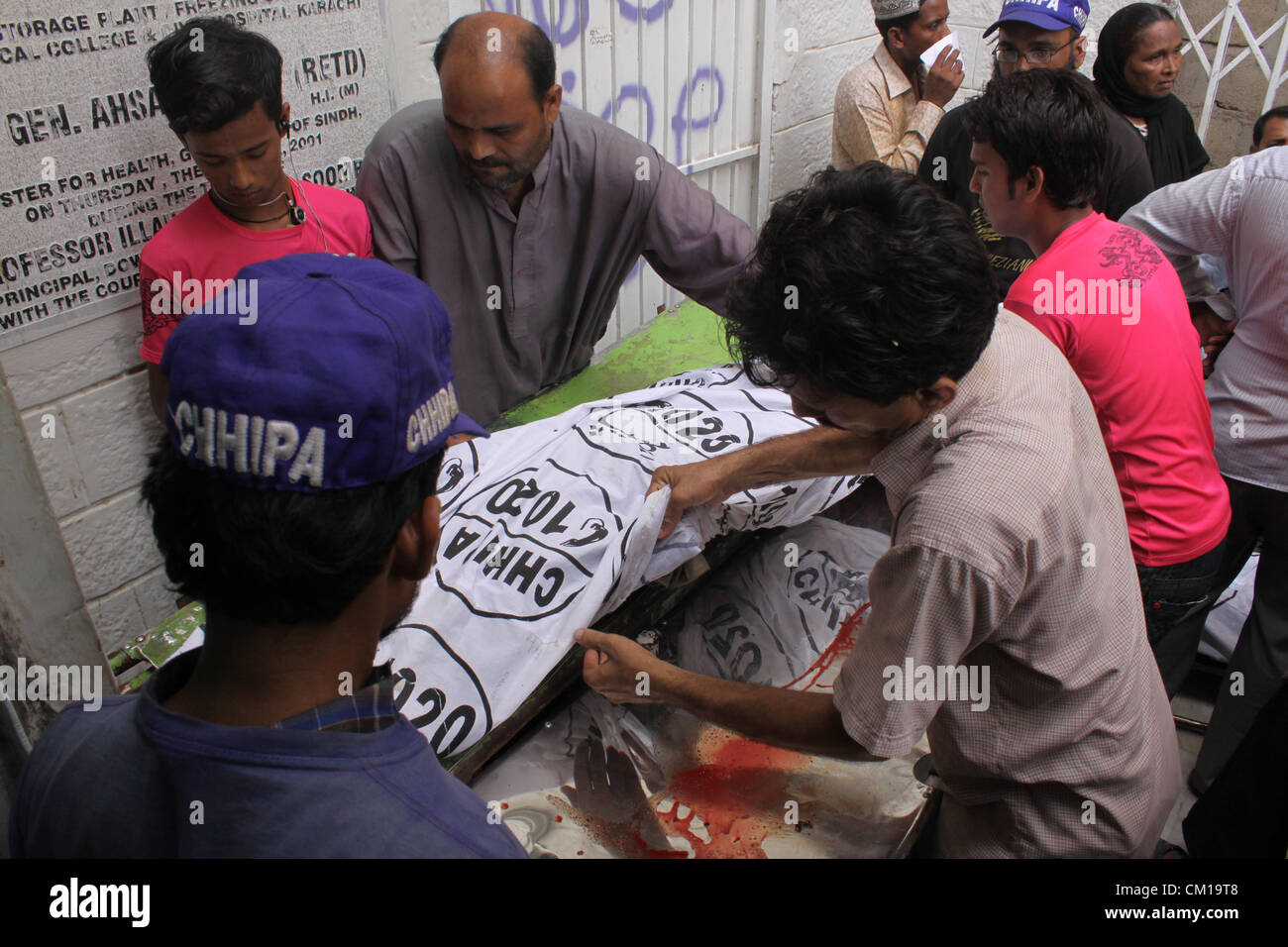 Karachi, Pakistan. 12th September, 2012. Rescue workers move a burnt dead body of a factory worker at a hospital in Karachi September 12, 2012. Atleast 289 workers were burnt when fire engulfed a garment factory in Karachi. Stock Photo