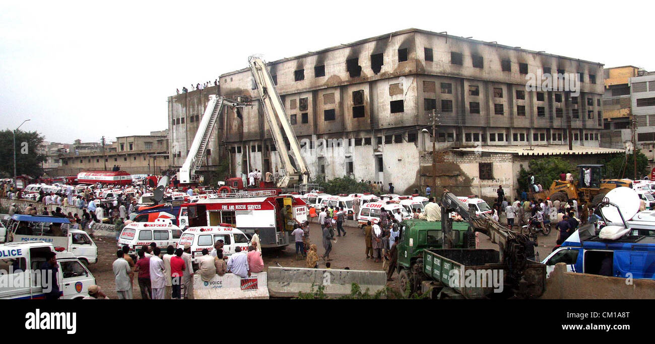People gather as rescue work is in progress at a burnt garment factory