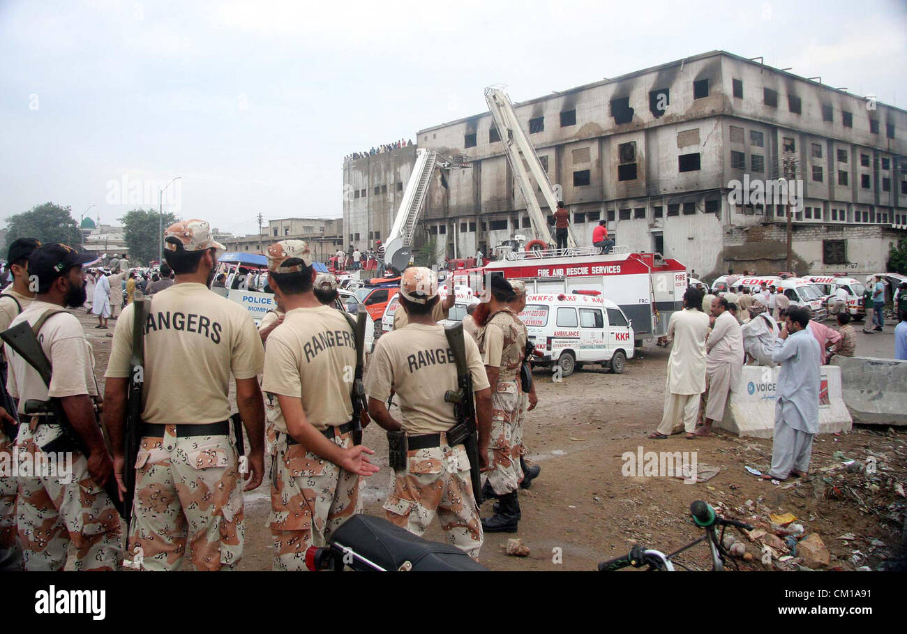 People gather as rescue work is in progress at a burnt garment factory