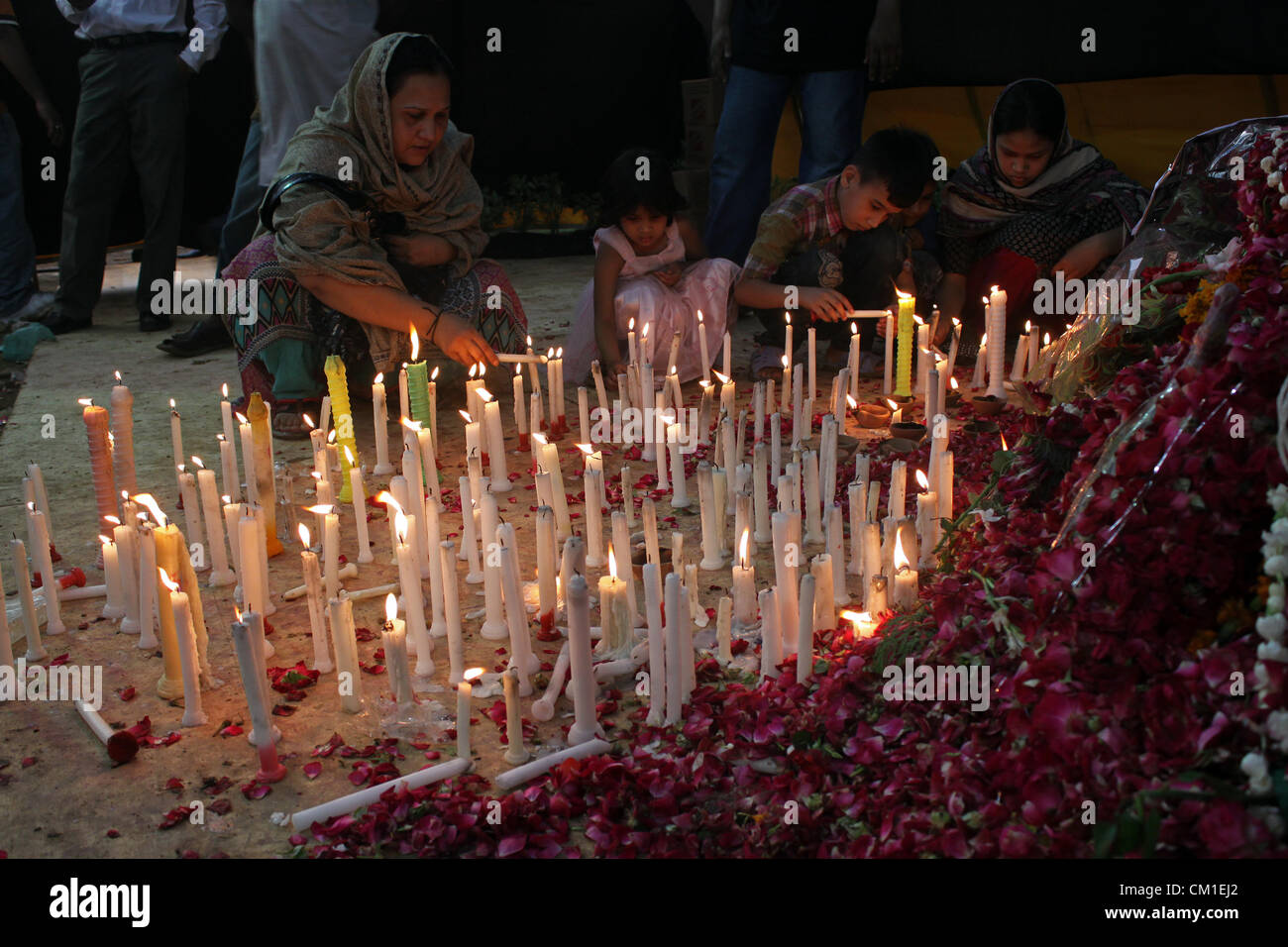Relatives of the burnt factory workers light candles at the site of the incident in Karachi, Pakistan on September 13, 2012. Atleast 289 factory workers were burnt when fire engulfed a garment factory on Wednesday. Stock Photo