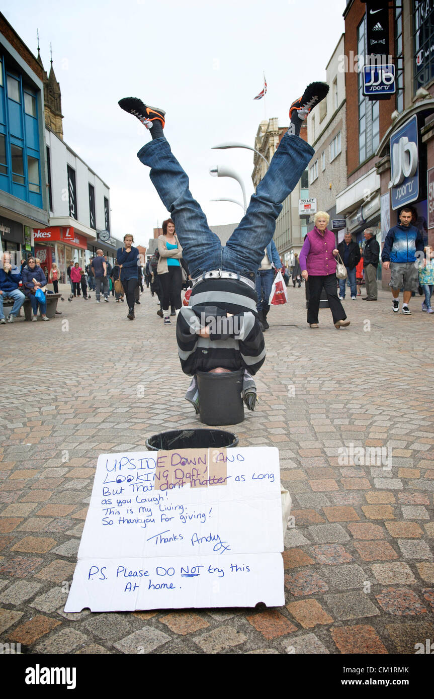 Blackpool, UK. Saturday 15th September 2012. Blackpool man turns upside down economy to his advantage.  'Upside down Andy' making a living standing upside down with his head in a bucket to the amusement of shoppers in Blackpool town centre. Stock Photo