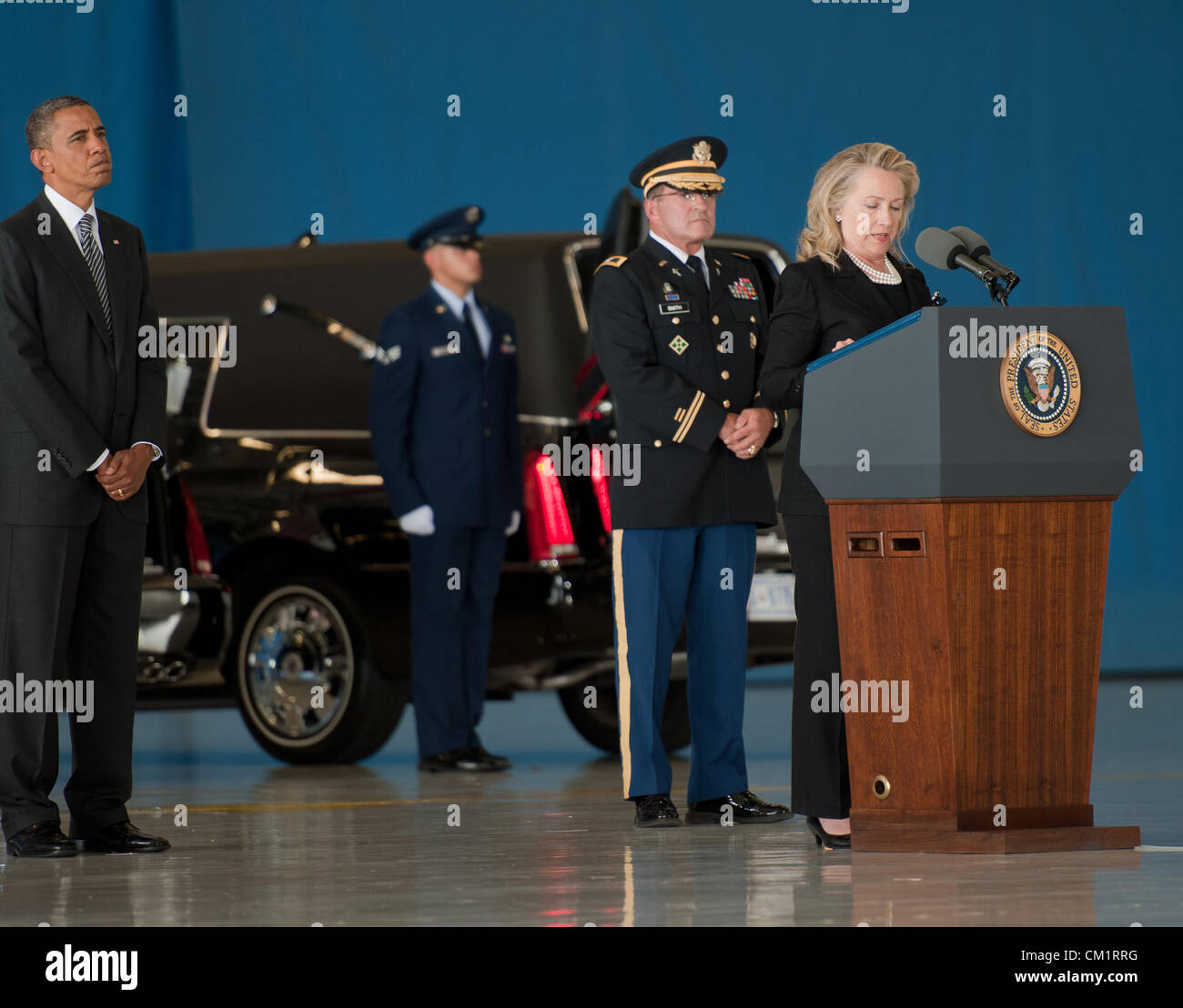 US Secretary of State Hillary Rodham Clinton speaks at a transfer ceremony for the four American's killed by mobs at the Benghazi Consulate as President Barack Obama looks on September 14, 2012 at Joint Base Andrews, Maryland. Stock Photo