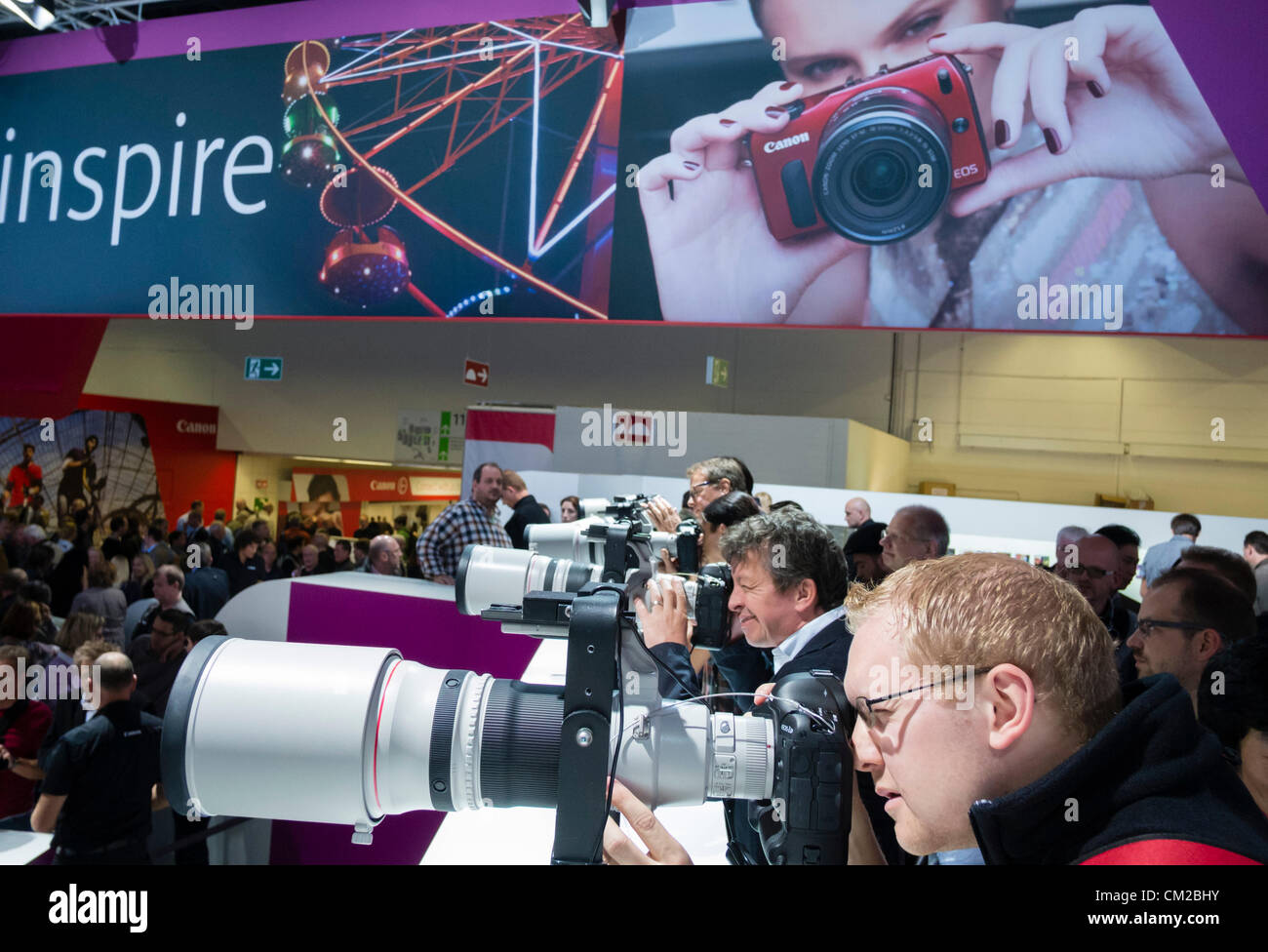 Visitors to the Canon stand try out a selection of large telephoto lenses on the second day of bi-annual Photokina photography and imaging trade fair held in Cologne Germany; Wednesday 19 September 2012. Stock Photo