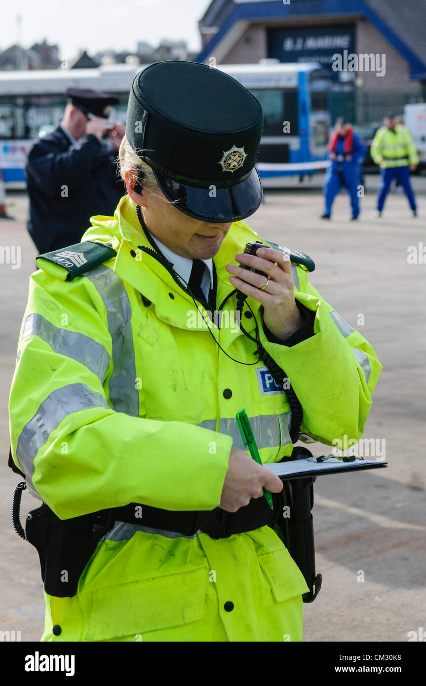 Female police officer uses a two-way radio to communicate to base station. Stock Photo