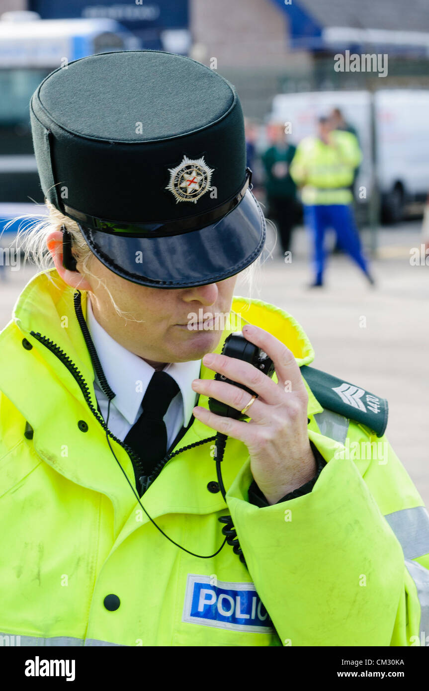 Female police officer uses a two-way radio to communicate to base station. Stock Photo