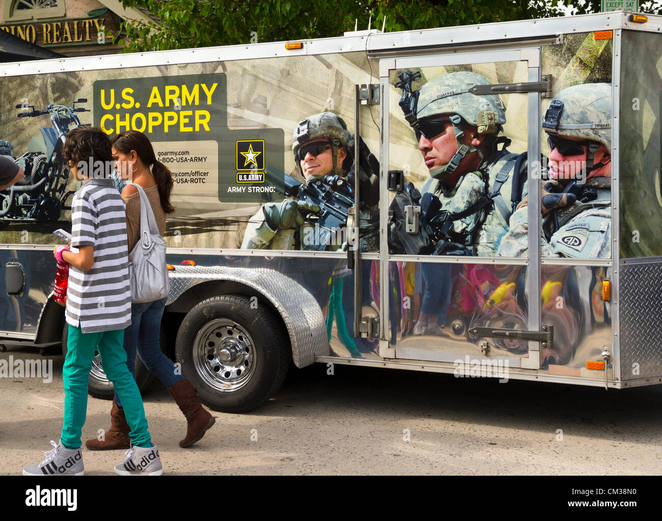 Sept. 22, 2012 - Bellmore, New York U.S. - At the Military Expo section of the 26th Annual Bellmore Family Street Festival, a woman and boy walk by truck with 'U.S. Army Chopper' (motorcycle) written on it, and scene of several soldiers, at Long Island fair. Stock Photo