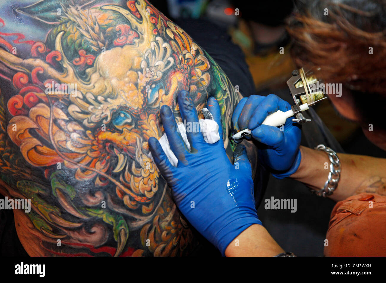 London, UK. 28th September 2012. Tattooist Gao Bin of Lion King Tattoo from Taiwan tattooing at the London Tattoo Convention 2012 Stock Photo