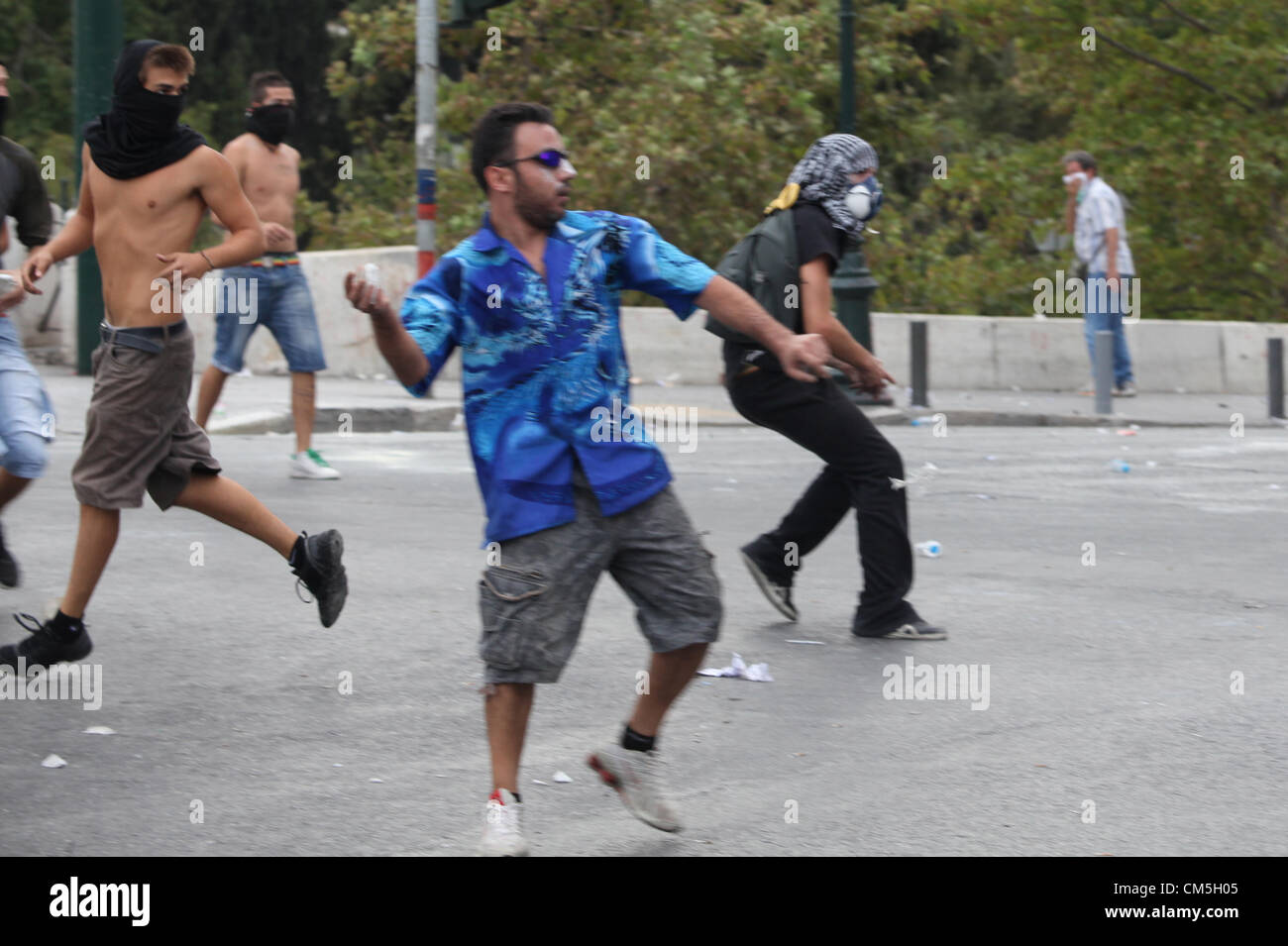 Tuesday 09 October 2012  Pictured: Protesters throwing stones to riot police in Syntagma Square, infront of the Greek Parliament.  Re: German Chancellor Angela Merkel has pledged her country's continuing support to Greece, during her first visit to Athens since the eurozone crisis erupted nearly three years ago.  Mrs Merkel said Greece had made good progress in dealing with its vast debt but that it was on a 'difficult path'.  Thousands of people who blame Germany for forcing painful austerity measures on Greece are protesting in Athens.  Police have used teargas and stun grenades against demo Stock Photo