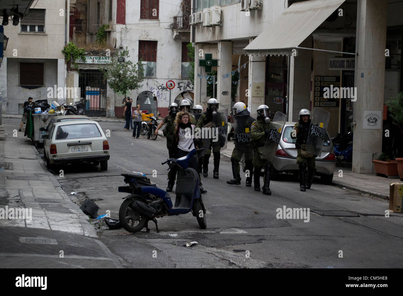 Greek riot policemen use a young girl as a human shield to stones thrown at their unit. Stock Photo