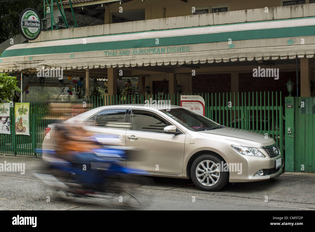 Oct. 11, 2012 - Bangkok, Thailand - A motorcycle taxi passes a Toyota Camry on a street in Bangkok, Thailand. About 160,000 units of Toyota's popular Camry and Corolla models produced between March 21, 2006 and May 31, 2010 in Thailand are part of Toyota Motor's global recall. Toyota Motor Corp said yesterday it would recall more than 7.4 million vehicles worldwide because the faulty power window switch was a potential fire hazard, the latest in a series of setbacks that have dented the reputation of Japan's biggest automaker. The voluntary move is the biggest single recall since Ford pulled 8 Stock Photo