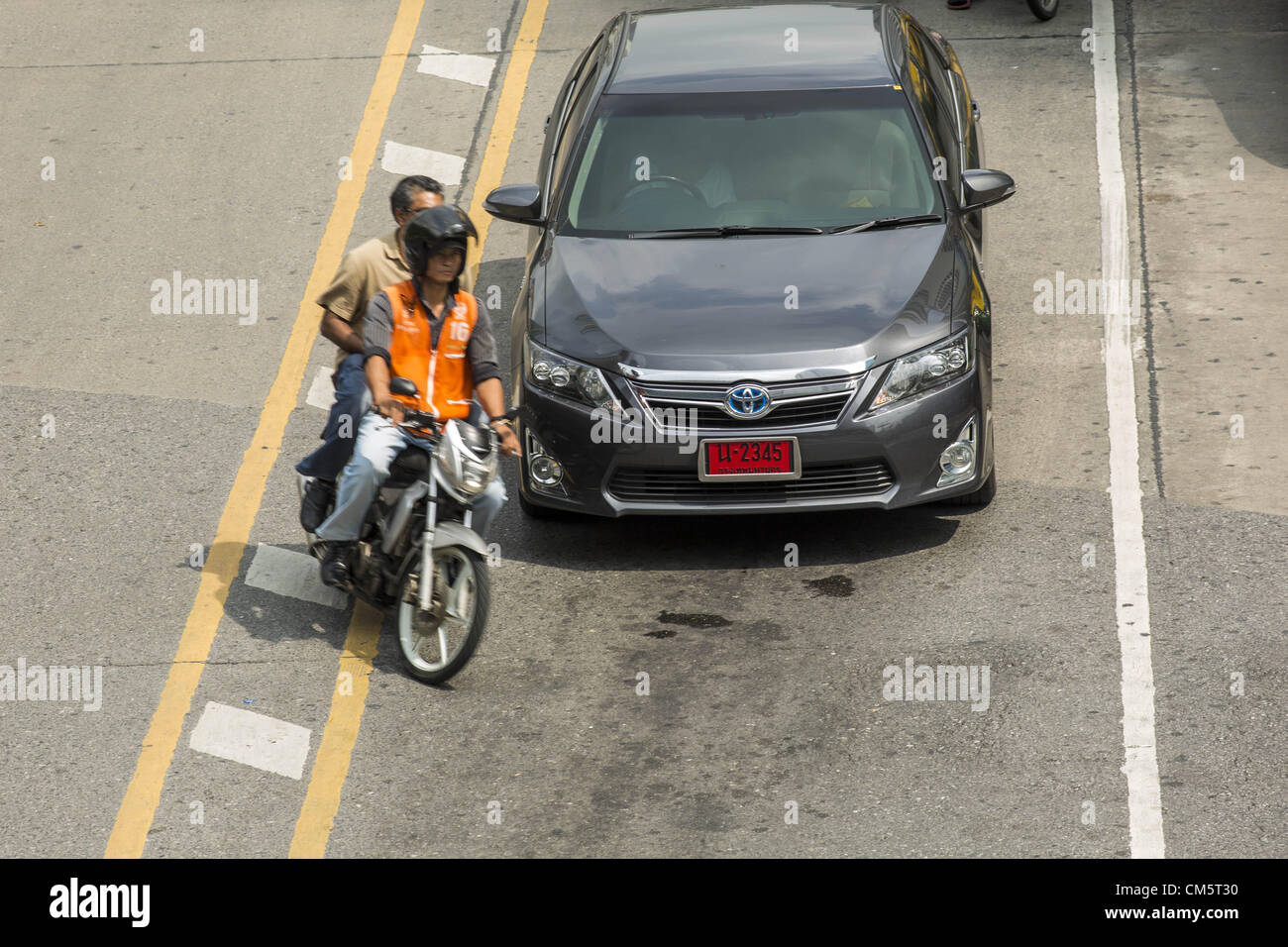 Oct. 11, 2012 - Bangkok, Thailand - A motorcycle taxi pulls in front of a Toyota Camry on a street in Bangkok, Thailand. About 160,000 units of Toyota's popular Camry and Corolla models produced between March 21, 2006 and May 31, 2010 in Thailand are part of Toyota Motor's global recall. Toyota Motor Corp said yesterday it would recall more than 7.4 million vehicles worldwide because the faulty power window switch was a potential fire hazard, the latest in a series of setbacks that have dented the reputation of Japan's biggest automaker. The voluntary move is the biggest single recall since Fo Stock Photo