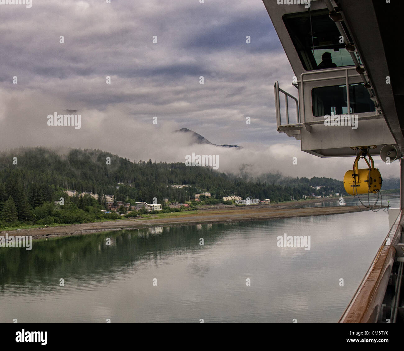 July 5, 2012 - Borough Of Juneau, Alaska, US - A pilot on the flying bridge steers the Holland America Lines ms Zaandam up the Gastineau Channel as low lying clouds and morning mist hang over the town of Douglas on Douglas Island, just across the channel from Juneau, obscuring the mountains of the Coast Range. (Credit Image: © Arnold Drapkin/ZUMAPRESS.com) Stock Photo