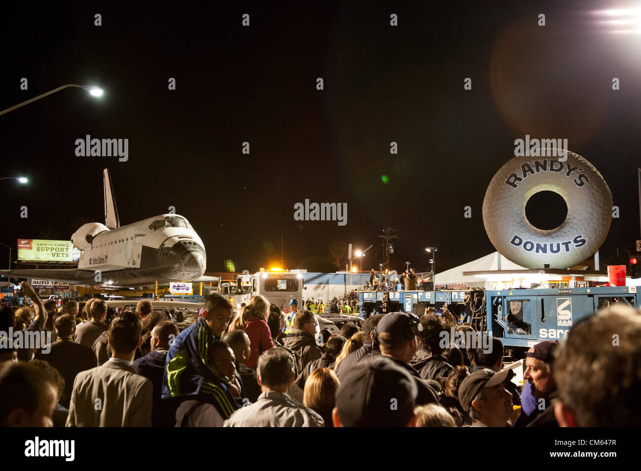 Inglewood, Los Angeles, CA, USA- 12 October, 2012 - The Space Shuttle Endeavour is towed through the streets of Los Angeles on its way to its permanent home at the California Science Center, making a nighttime stop near the landmark Randy's Donuts at La Cienega and Manchester Blvd where a Toyota Tundra truck will replace the heavier transport to tow it across the bridge over the 405 Freeway. The Shuttle was decommissioned in 2011 when the NASA space program was discontinued. Stock Photo