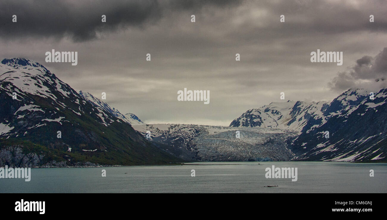 July 3, 2012 - Glacier Bay, Alaska, US - The impressive Reid Glacier in Glacier Bay, surrounded by the mountains of the Fairweather Range, has its origins in the Brady Icefield. At the waters edge, its width is 0.75 miles (1.21Â km), and its face rises to a height of 150 feet (46Â m). Its fast rate of retreat has turned it from a tide water to terrestrial glacier, as glacial sediment deposits have gradually filled the eastern and western margins at its inlet. Glacier Bay covers 3.3 million acres (1.3 million hectares) of rugged mountains, dynamic glaciers, temperate rainforest, wild coastlines Stock Photo