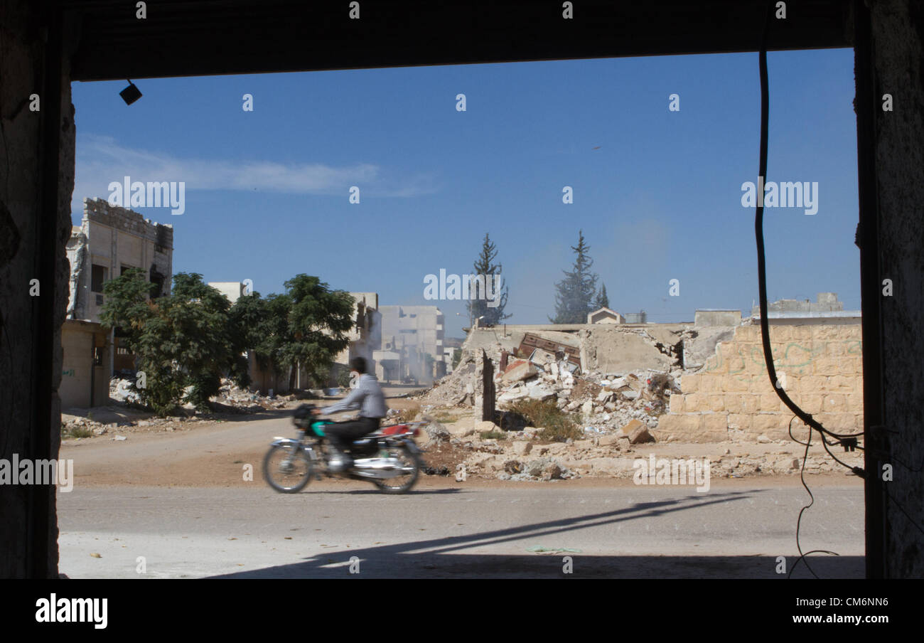 Azaz, Syria. 17th October 2012. A man rides by a building destroyed by ...
