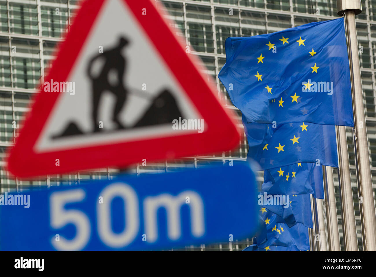 Brussels, Belgium. 18th October, 2012. European Council meeting (Brussels 18-19 October 2012). Picture shows European Union flags behind a roadworks sign outside the Charlemagne Building, Brussels, ahead of the European Council meeting where European leaders will meet to discuss the mounting debt crisis across Europe. Stock Photo