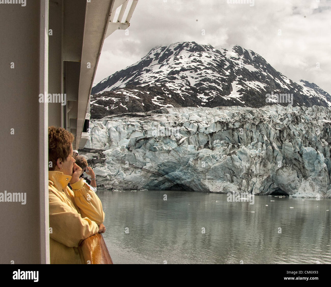 July 3, 2012 - Glacier Bay, Alaska, US - Passengers cruising in Glacier Bay view the impressive Lamplugh Glacier from their balconies on the Holland America Lines ms Zaandam. Originating in the Brady Icefield the glacier stretches over 16 miles (26Â km) and has a width of about 0.75 miles (1.21Â km) at the water face and rises to heights of 150â€“160 feet (46â€“49 m). Glacier Bay covers 3.3 million acres (1.3 million hectares) of rugged mountains, dynamic glaciers, temperate rainforest, wild coastlines, deep sheltered fjords and wildlife. A highlight of the Alaskan Inside Passage and part of a Stock Photo