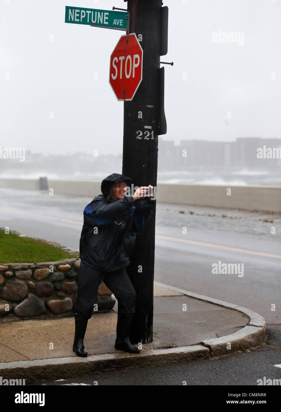 Winthrop, Massachusetts, USA. A woman braces herself against the wind from Hurricane Sandy as she photographs the waves coming ashore in Winthrop, Massachusetts, Monday, Oct. 29, 2012. The huge weather system  is predicted  to make landfall in southern New Jersey late Monday and is affecting weather up and down the East Coast of the United States. Stock Photo