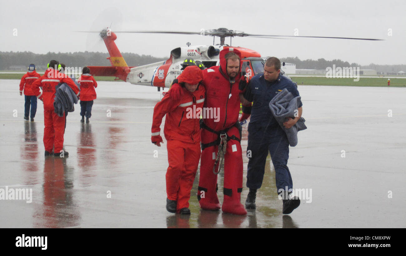 Ground crew from Coast Guard Air Station Elizabeth City, N.C., assist one of the sailors from the tall ship Bounty from an MH-60 Jayhawk helicopter to a hanger at the air station Monday, Oct. 29, 2012. Two Jayhawk aircrews hoisted 14 survivors from the Bounty after the survivors abandoned the ship when it began taking on water 90 miles southeast of Cape Hatteras, N.C., during Hurricane Sandy. U.S. Coast Guard photo by Lt. Zach Huff/Archive Image Stock Photo