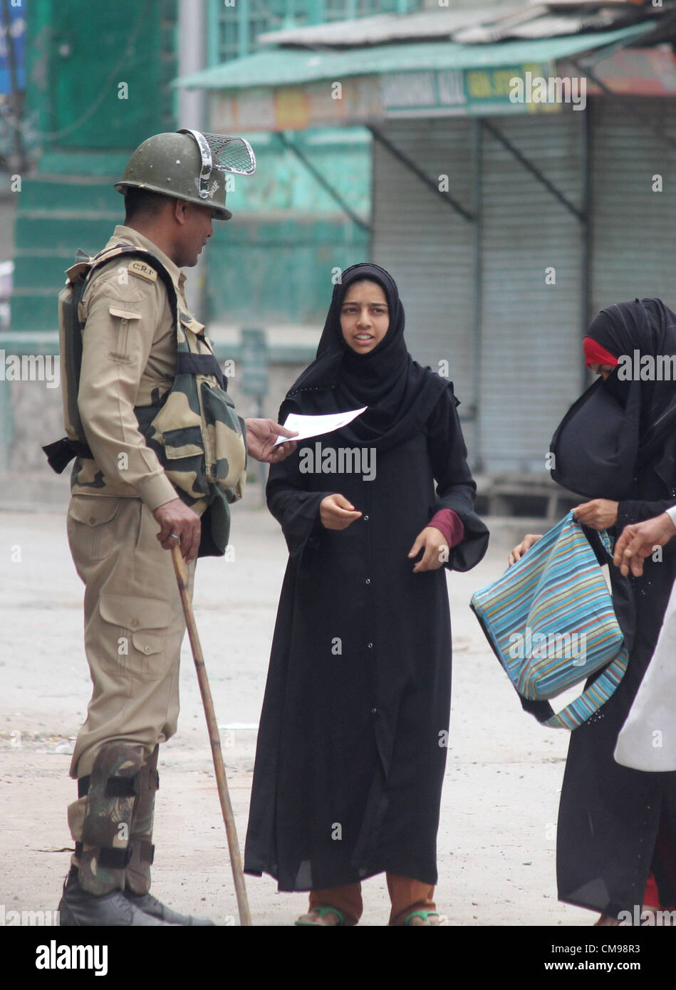 indian Central Reserve Police Force (CRPF) member questioning a Kashmiri Muslim woman during a curfew in Srinagar, the summer capiatl of indian kashmir  on  27,6. 2012. A major fire gutted a 350-year-old, revered Sufi Muslim shrine in Indian Kashmir June 25,Thousands of Indian forces patrolled tense streets in Kashmir's main city on Wednesday as residents boycotted work for a third straight day to protest the fiery destruction of a 350-year-old Muslim shrine.Shops, businesses and schools remained closed in Srinagar, while public buses and taxis were nowhere to be found. Police asked residents  Stock Photo