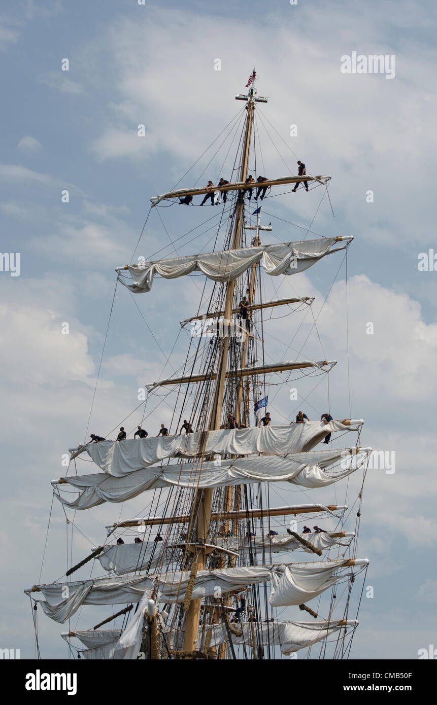 US Coast Guard cadets furl the sails on America's tall ship Eagle as it docks at its home port of Fort Trumbull, New London, Connecticut where it can often be seen in the summer. The Eagle is the only active-duty sailing vessel in America's military.    Original Live News Caption: New London, Connecticut, USA - July 7, 2012: The US Coast Guard tall ship Eagle lands at Fort Trumbull during the OpSail 2012 festival. Cadets high up in the rigging furl the sails after the Parade of Sail during festivities commemorating the bicentennial of the War of 1812. Stock Photo