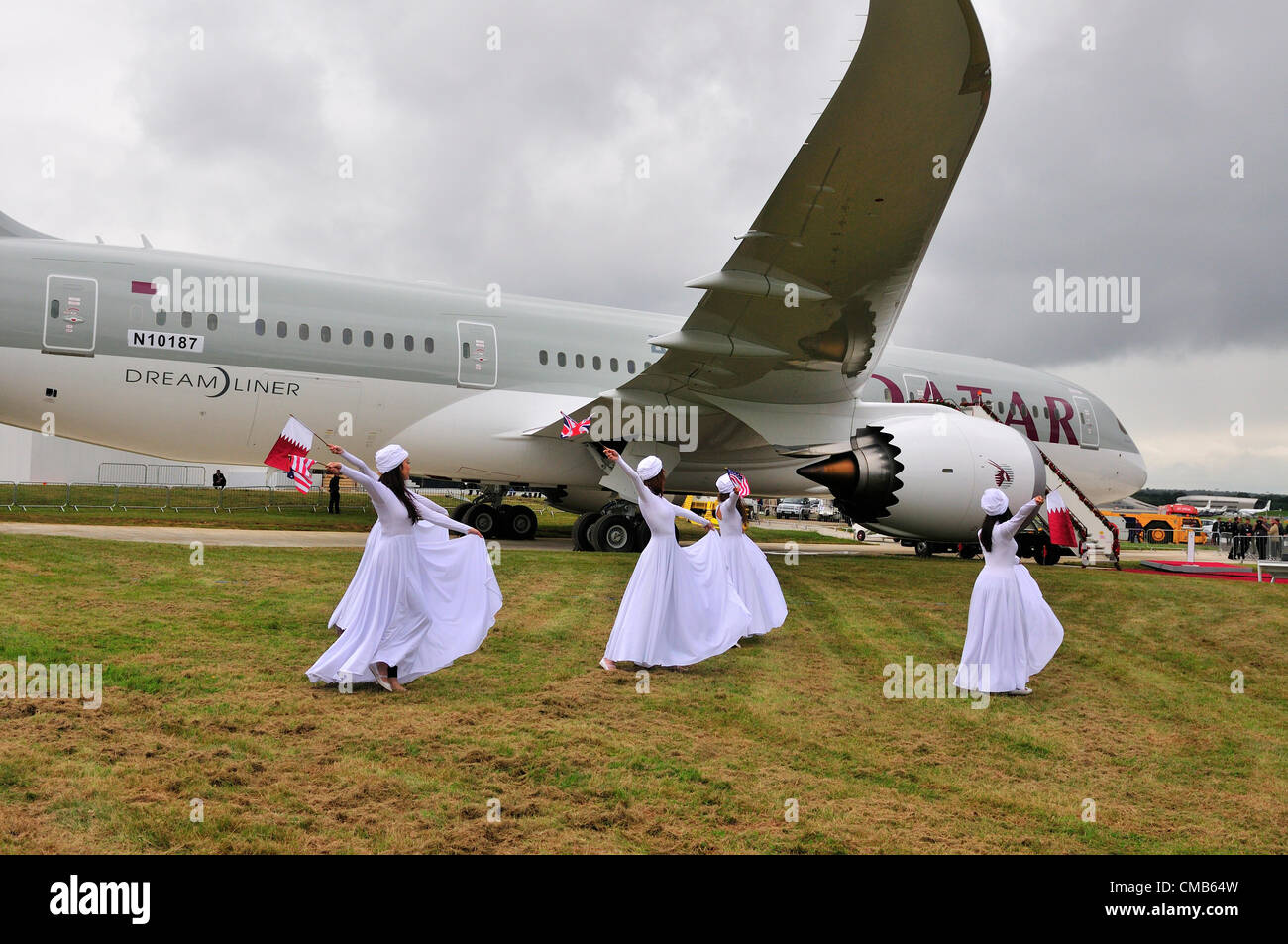 Farnborough, UK. Monday 9th July 2012.  Qatar Airways dancers dance around the US Plane maker Boeing 787  jet ‘Dreamliner’ at the Farnborough International Airshow 2012 which started today. It is seen as a rival to European Airbus at the Farnborough air show. Qatar Airways participated for the first time in flying displays at the Farnborough International Airshow. Stock Photo