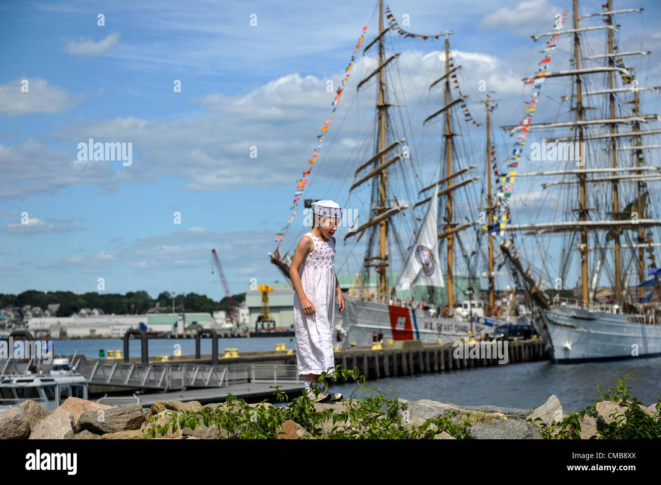 The young sister of a US Coast Guard cadet climbs along the shore in front of America's tall ship the historic three-masted barque Eagle in its home port of Fort Trumbull in New London Connecticut where it is usually docked and can be visited in summer and the Brazilian tall ship, the Cisne Branco (White Swan). Her sister is a cadet training on the Eagle (I also have a photo of them together - . See CMB8XW). Please see original Live News Caption in Optional Info. Stock Photo