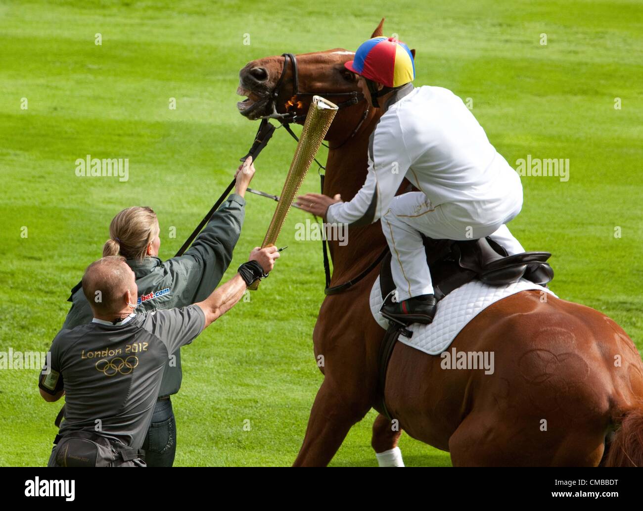 10-07-2012 : Ascot, UK - The London 2012 Olympic Torch visiting Ascot Racecourse. Denise Lewis carried the torch and passed it to jockey Frankie Dettori who carried the torch on horseback. Stock Photo