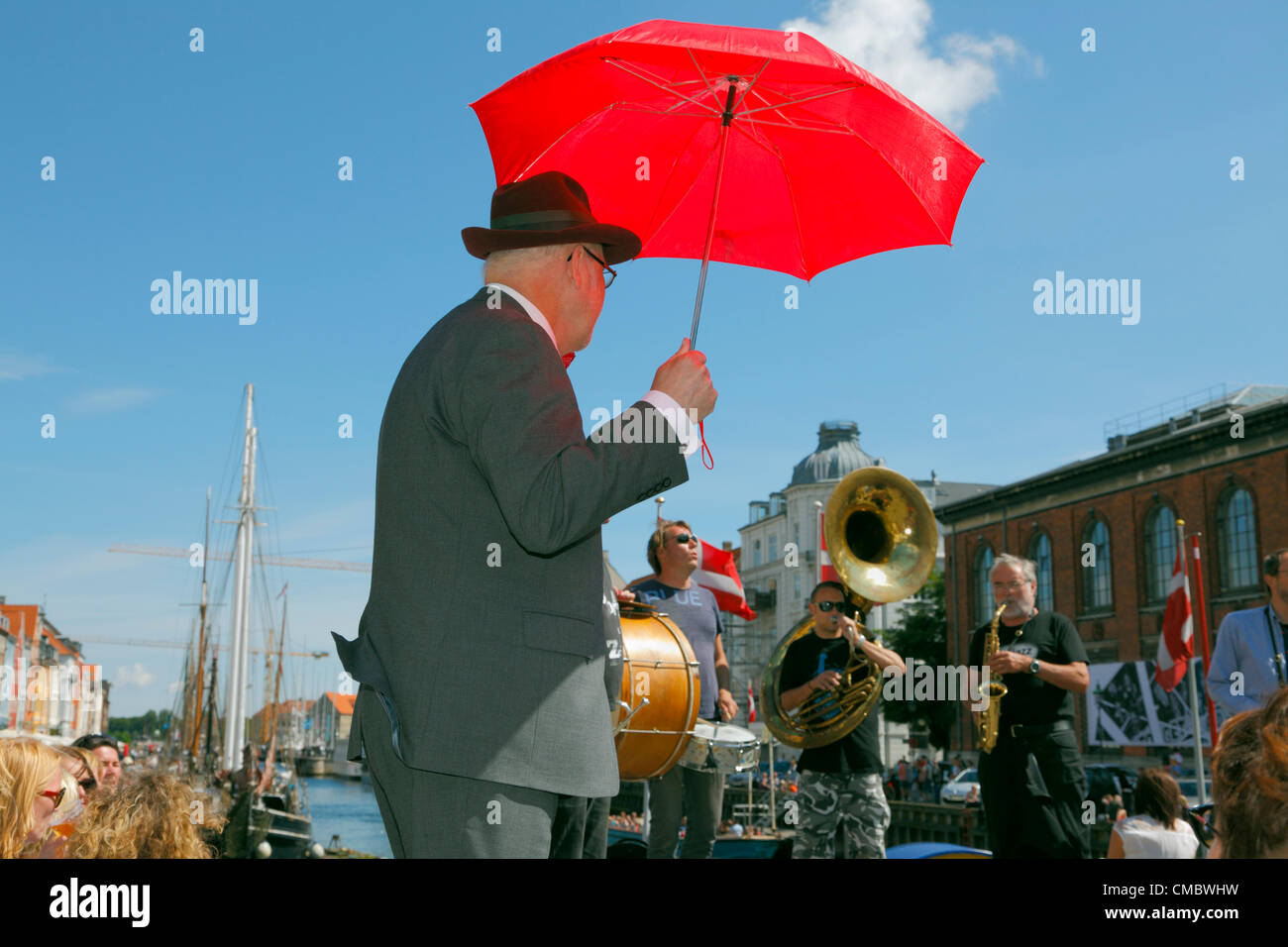 July Friday 13, 2012 -  The popular street parade and traditional jazz band - The Orion Brass Band playing with performer and atmosphere creator in crowded Nyhavn, Copenhagen, Denmark, on a hot and sunny Friday afternoon full of tourists during The Copenhagen Jazz Festival. Stock Photo