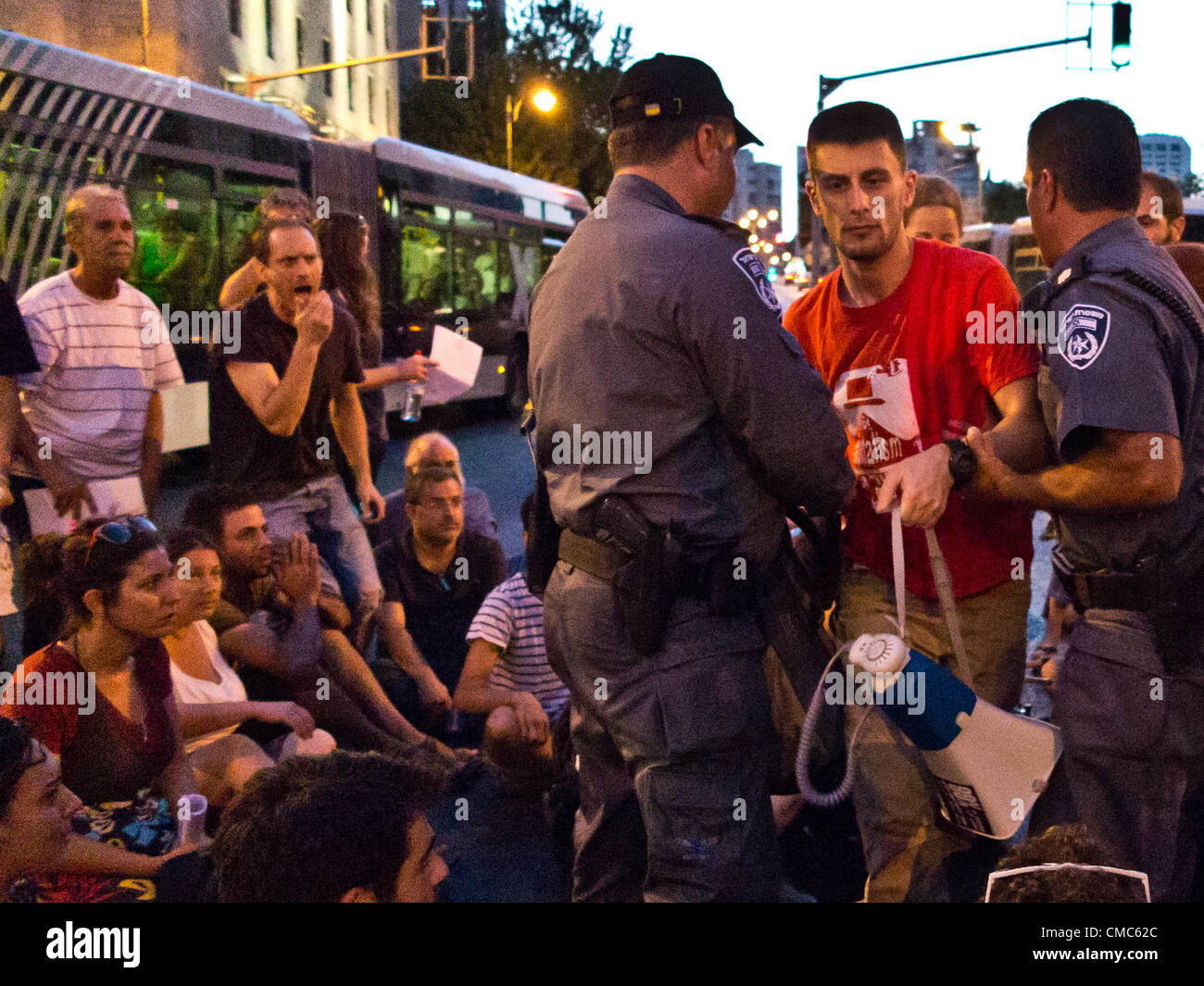 Police arrest a social welfare activist who incits protesters to obstruct traffic as they sit on King George Street at Kikar paris Square chanting “We are all Moshe Silman!”. Jerusalem, Israel. 15-July-2012.  Social welfare activists protest following incident yesterday in Tel-Aviv in which Moshe Silman lit himself on fire, staging a 'March of Rage' from a recently erected tent-camp in Independence Park to the PM's residence and then downtown. Stock Photo