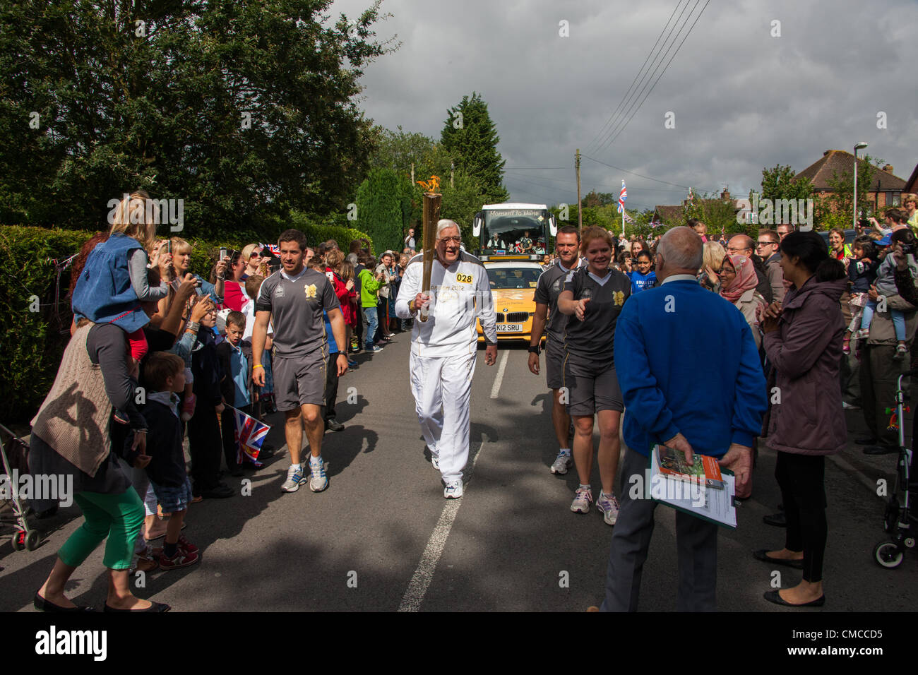 Copthorne, West Sussex, UK. 17th July, 2012. The Olympic Torch is carried through Copthorne by Derek Day. Derek played in the Great Britain hockey team which won a bronze medal in the 1952 Olympic Games. At that time there were only 11 medals given out and so both he and one of the other squad members missed out on receiving a medal. In partnership with the BOA, GB Hockey was able to put this right in 2010 he was given a medal made from the original cast. Stock Photo