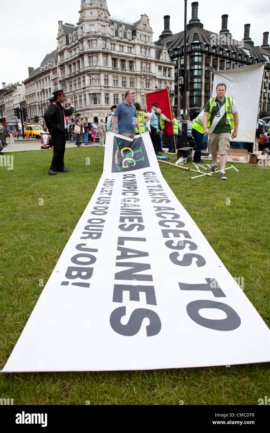 London, UK - 17th July 2012. Black cab drivers erect a banner in Parliament Square. Hundreds of London black cab drivers protested today for the right to use London 2012 Olympic games lanes. The cabbies drove at snail pace around Parliament Square and up Whitehall loudly sounding their horns. Some union protestors also erected banners on Parliament Square. The protest gridlocked many the aforementioned roads as well as many nearby routes.  Stock Photo