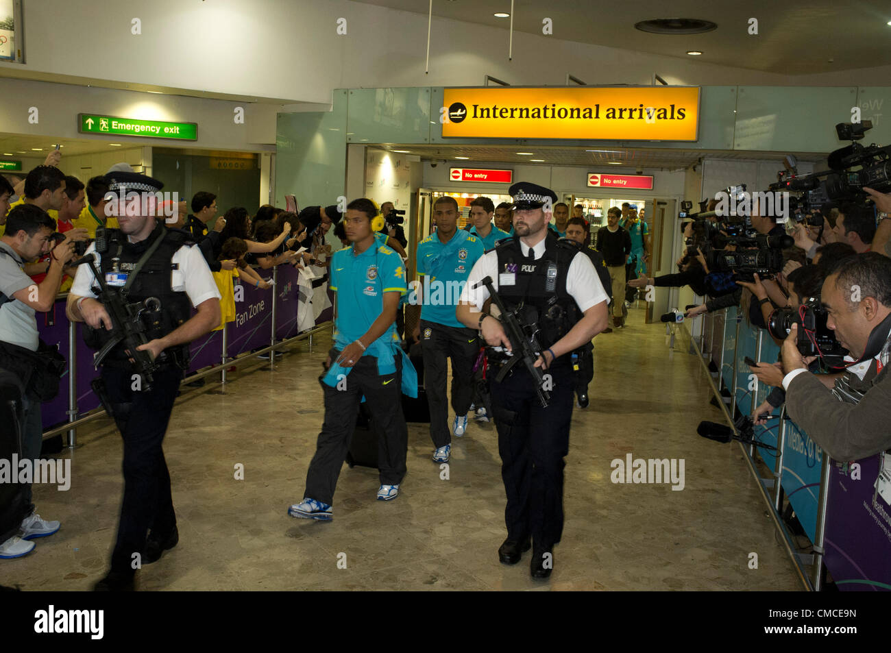 17th July 2012.  London Heathrow, UK.  Olympic Competitors and Officials arrive at Heathrow airport terminals. The Brazil Olympic Football team emerge from the airport terminal building with Police security . Stock Photo