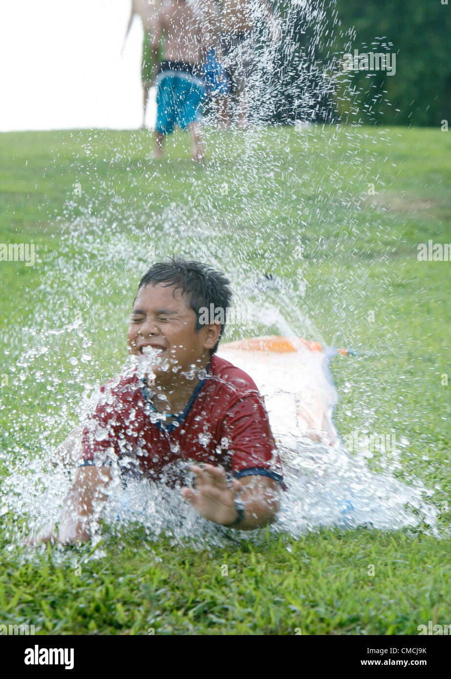 July 18, 2012 - Cordova, Tennessee, U.S. - July 18, 2012  - Alex Martinez,9, ploughs his way through the hose sprays on Wednesday afternoon. He and his friends found relief from the heat on a Slip and Slide which they set up behind their homes in Cordova. (Credit Image: © Karen Pulfer Focht/The Commercial Appeal/ZUMAPRESS.com) Stock Photo