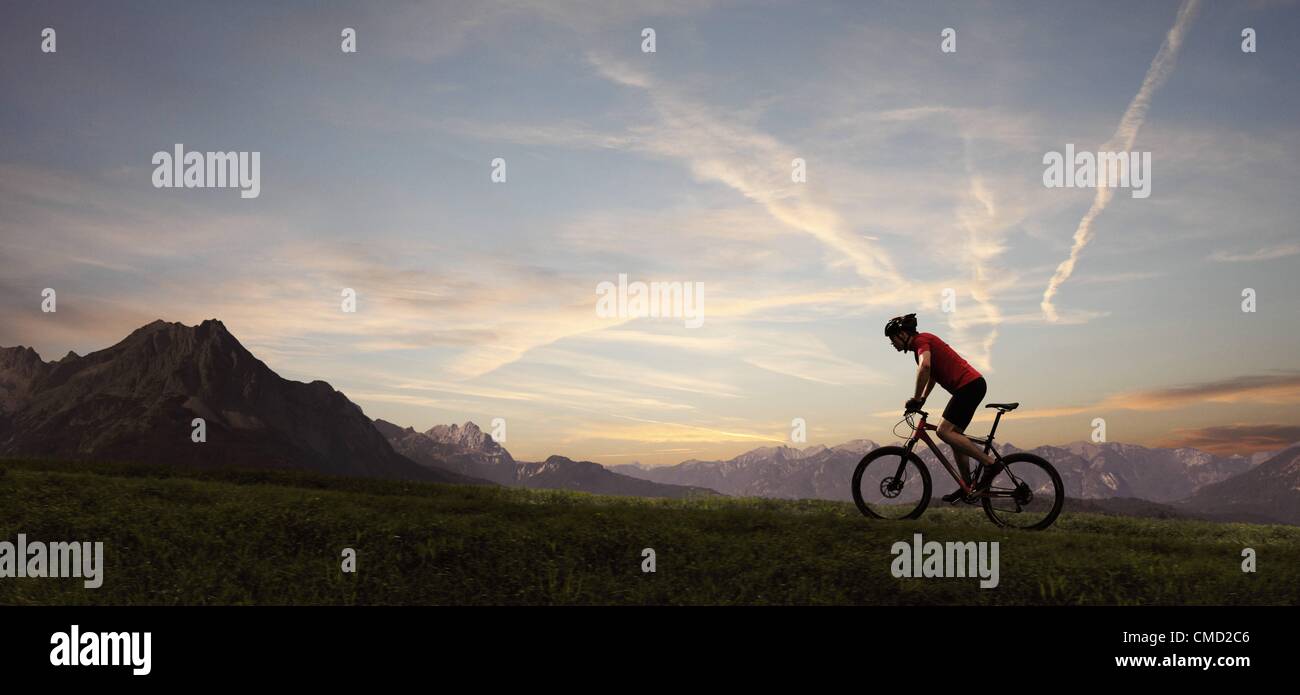 08.11.2011. Germany. Model released picture of a cyclist riding into the setting sun. Stock Photo