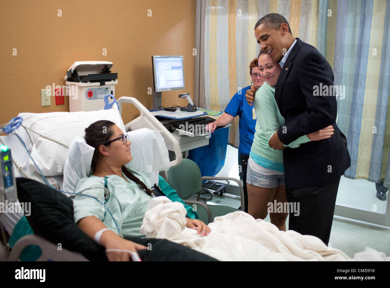 US President Barack Obama hugs Stephanie Davies, who helped keep her friend, Allie Young, left, alive after being shot during the movie theatre massacre July 22, 2012 in Aurora, Colorado. President Obama visited victims from the shooting at a mid-night showing of The Dark Knight Rises. Stock Photo