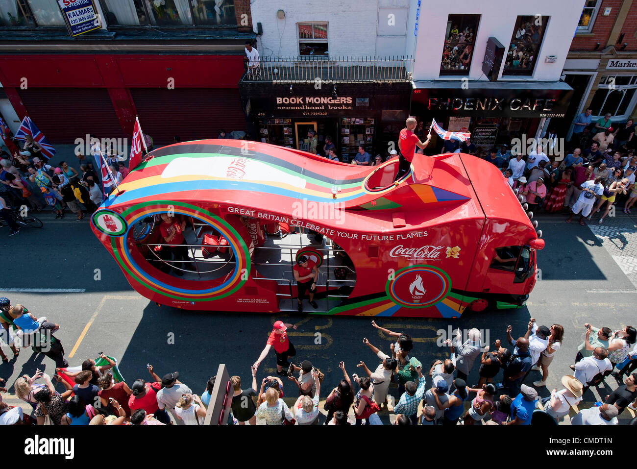 The Olympic Torch relay comes down Coldharbour Lane into Brixton, London, UK. The torchbearer is protected by the police in grey sportswear and the relay is preceded by sponsors vehicles which are booed by the crowd. 26 July 2012 Stock Photo