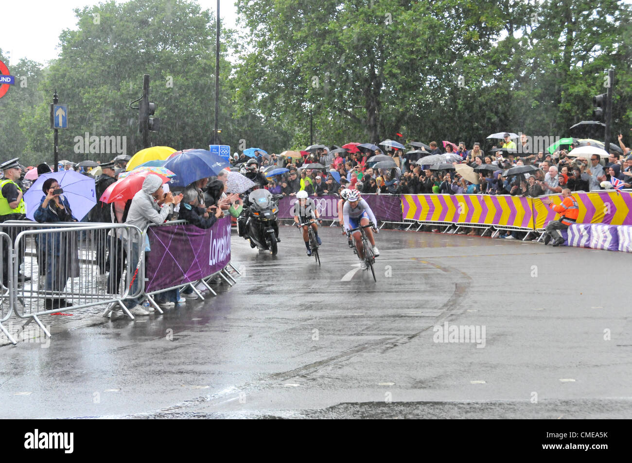 Hyde Park Corner, London, UK. 29th July 2012. The race leaders in the women's cycling road race at Hyde Park Corner approaches the end as the riders and crowd endure heavy rain and a thunderstorm. Stock Photo