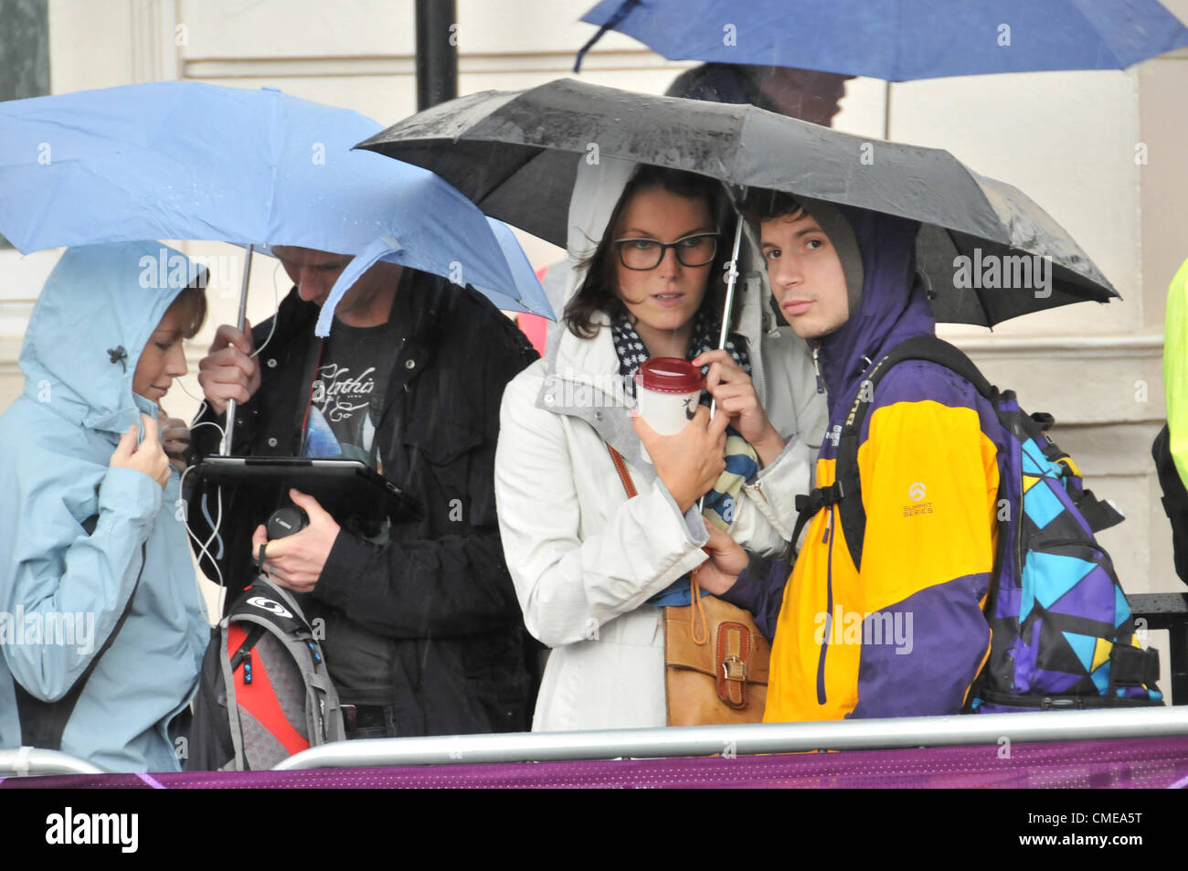 Hyde Park Corner, London, UK. 29th July 2012. The crowd try to stay dry as they watch the women's cycling road race at Hyde Park Corner as the race approaches the end as the riders and crowd endure heavy rain and a thunderstorm. Stock Photo