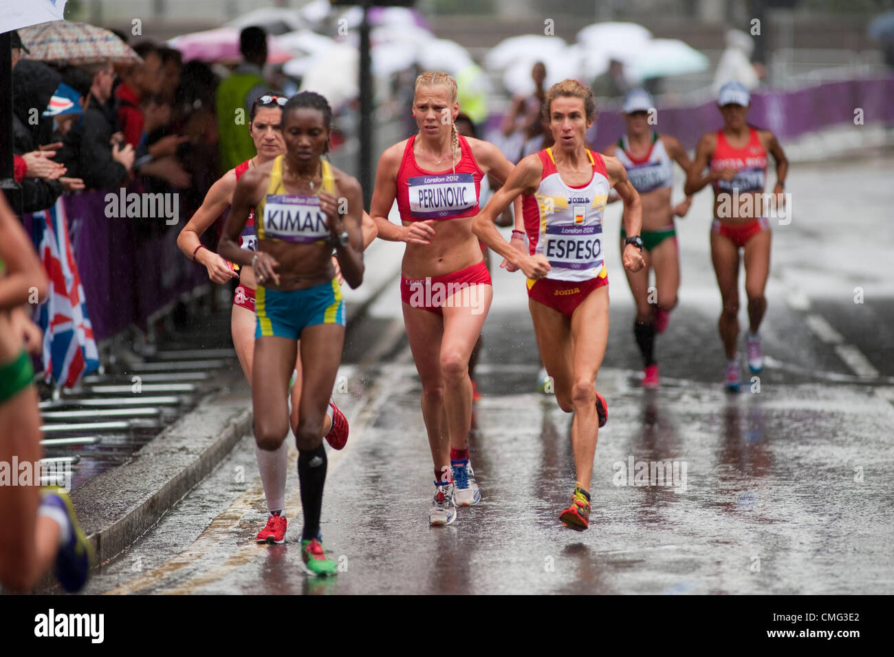 The London Olympic Games 2012 Womens Marathon Runners Approach The City Of London From The Embankment In Torrential Rain At 25 Minutes Into The Road Race Spectators Line The Route Sheltering Under