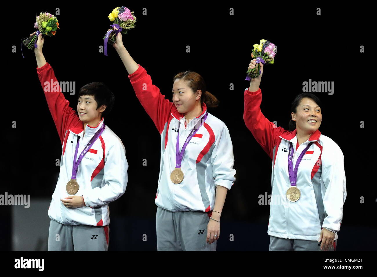 07.08.2012.  London, ENGLAND; Bronze medalists Tianwei Feng, Jiawei Li and Yuegu Wang of Singapore celebrate on the podium during the medal ceremony for the Women's Team Table Tennis gold medal match on Day 11 of the London 2012 Olympic Games at ExCeL. Stock Photo
