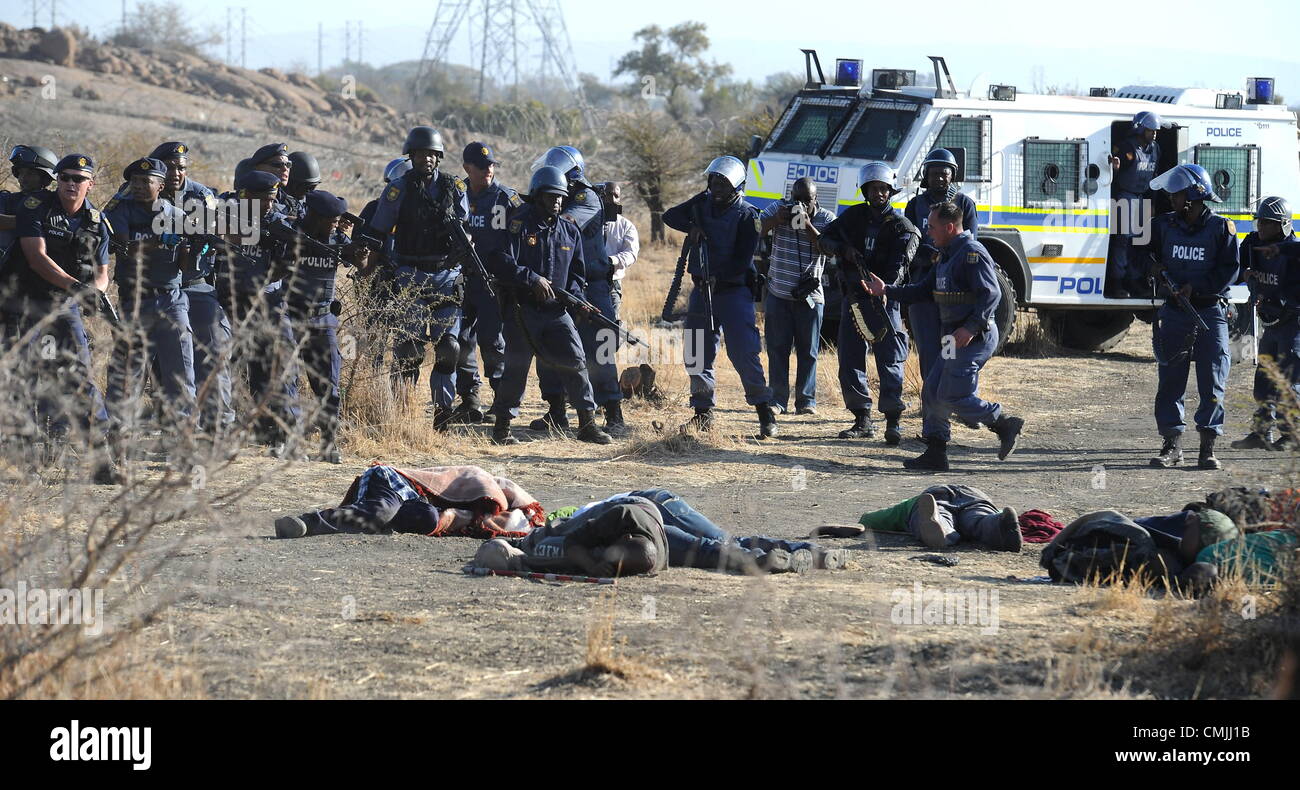16th Aug 2012. RUSTENBURG, SOUTH AFRICA: Police officers open fire on striking mine workers outside the Nkageng informal settlement on August 16, 2012 in North West, South Africa. It is unclear how many workers were killed in the shooting. Violence broke out in the area as workers downed tools during an apparent wage strike at the Lonmin Marikana Platinum Mine. (Photo by Gallo Images / Foto24 / Felix Dlangamandla). Credit:  Gallo images / Alamy Live News Stock Photo
