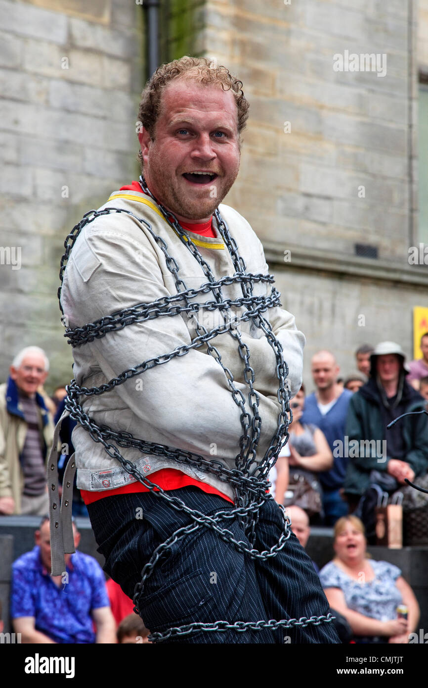 18 August 2012.  Byron Bertram, from Vancouver, Canada performing in Hunter Square, Edinburgh at the Edinburgh Fringe Festival. Byron Bertram was was performing an act of escapology using chains and a straight jacket at an outdoor venue. Stock Photo