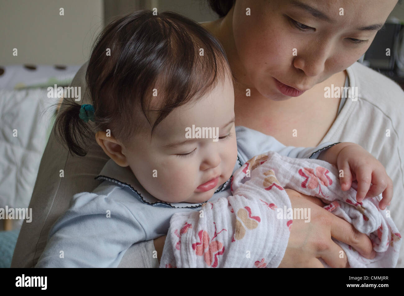 Cute mixed Asian (Korean) Caucasian baby girl being held by her Korean mother. Stock Photo