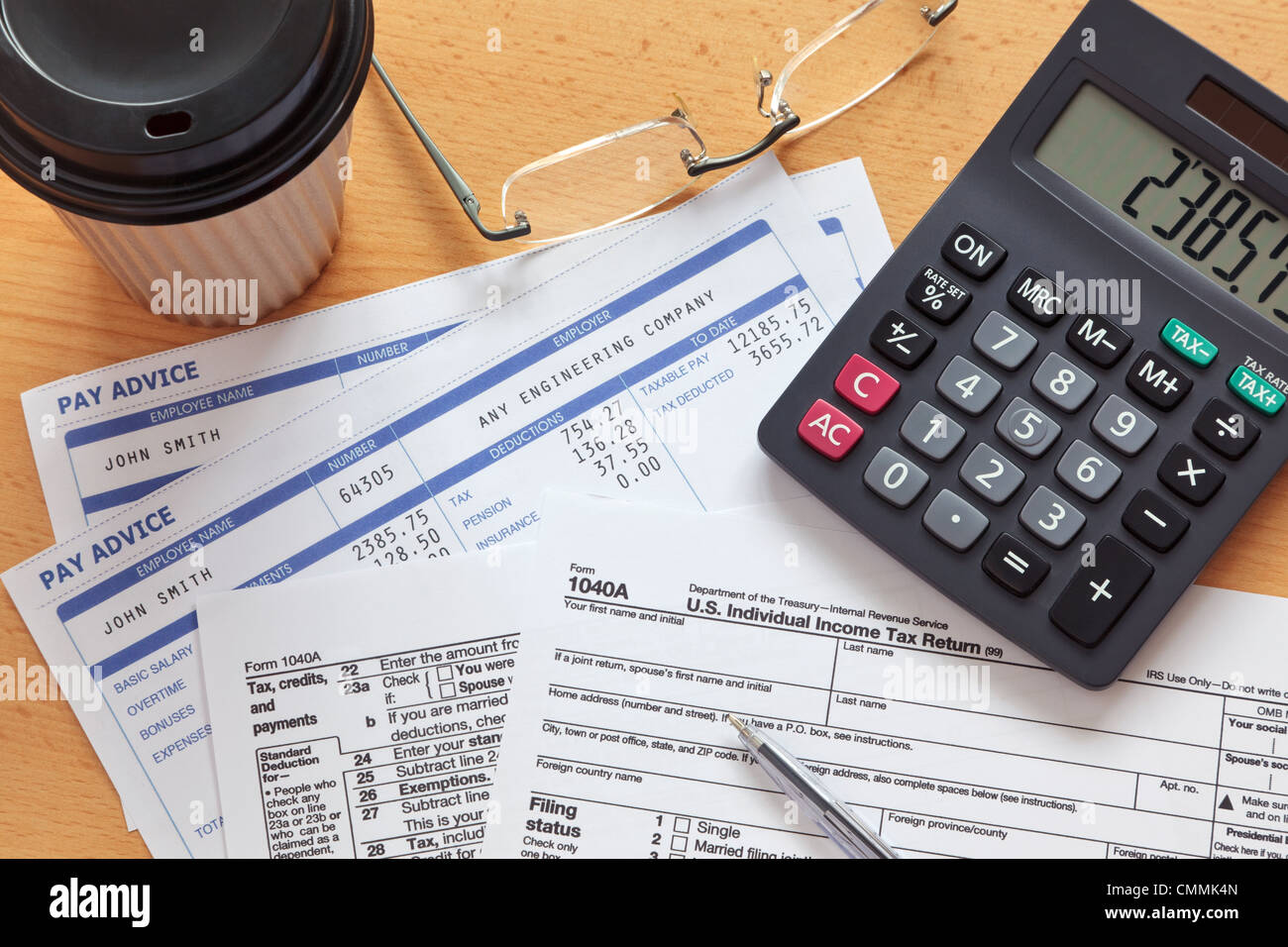 Photo of a 1040A tax form with payslips and a calculator. Stock Photo