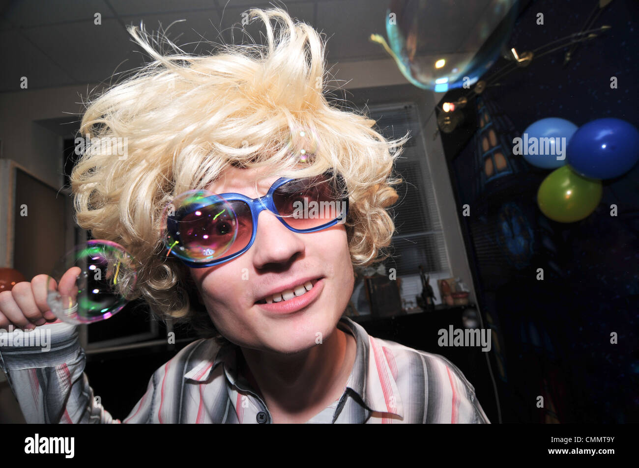 Young man wearing blond wig looks very drunk Stock Photo