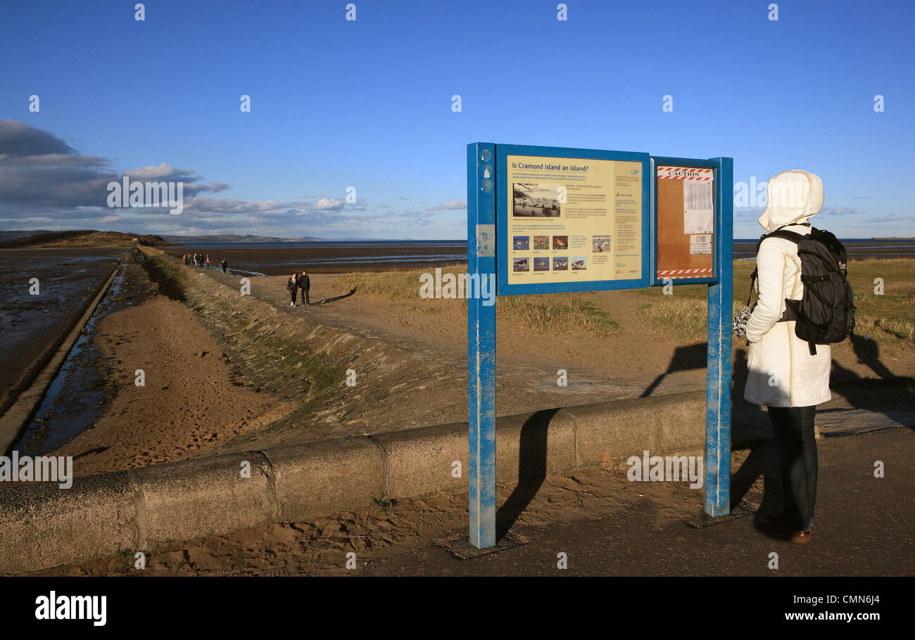 Woman reading the tide tables posted on a notice board at the causeway to  Cramond Island outside Edinburgh in Scotland Stock Photo - Alamy