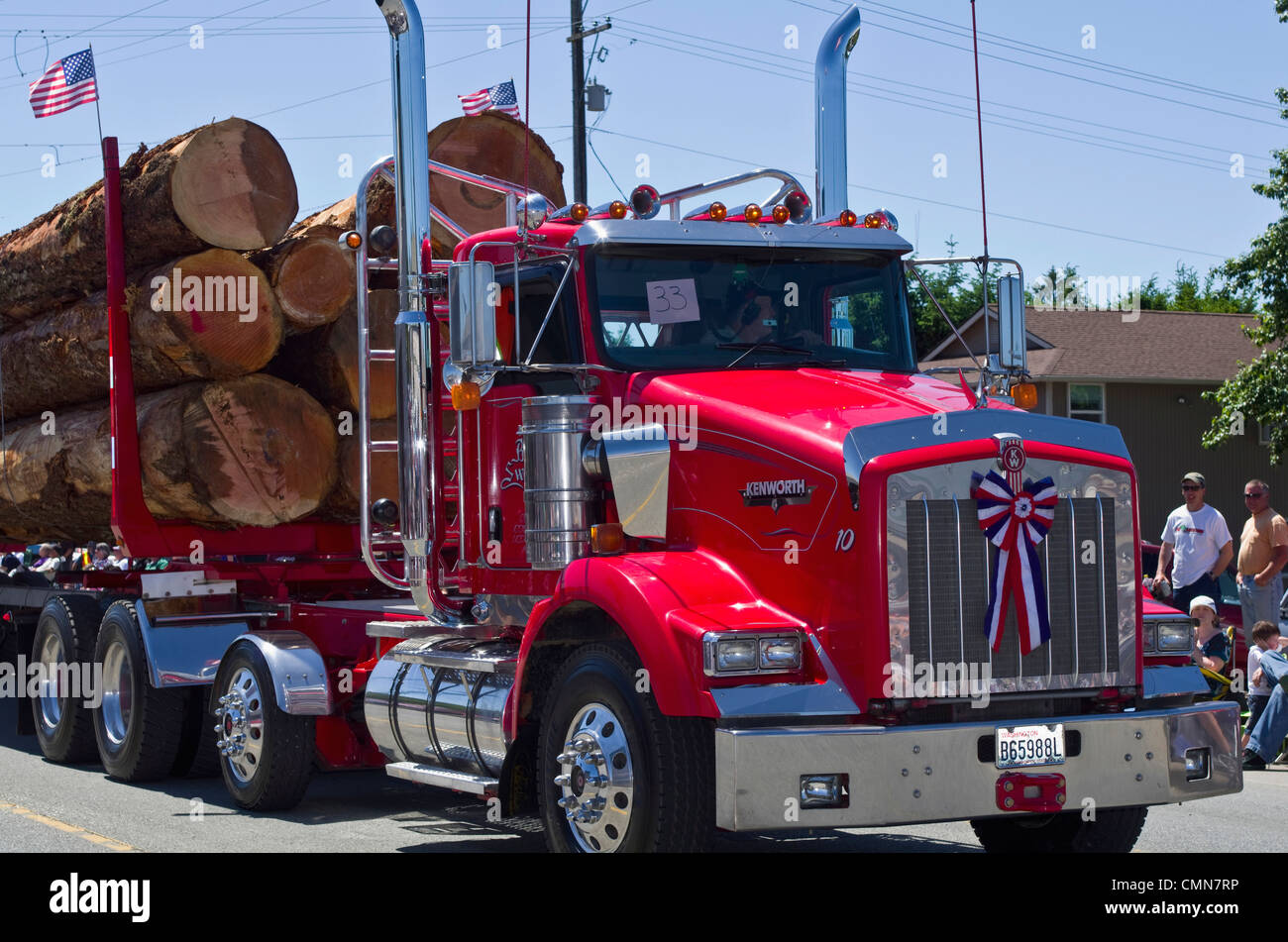 USA, Washington, Forks. Logging trucks with old growth logs in parade