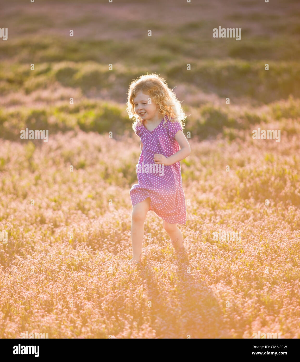 Caucasian girl running through field of flowers Stock Photo Alamy